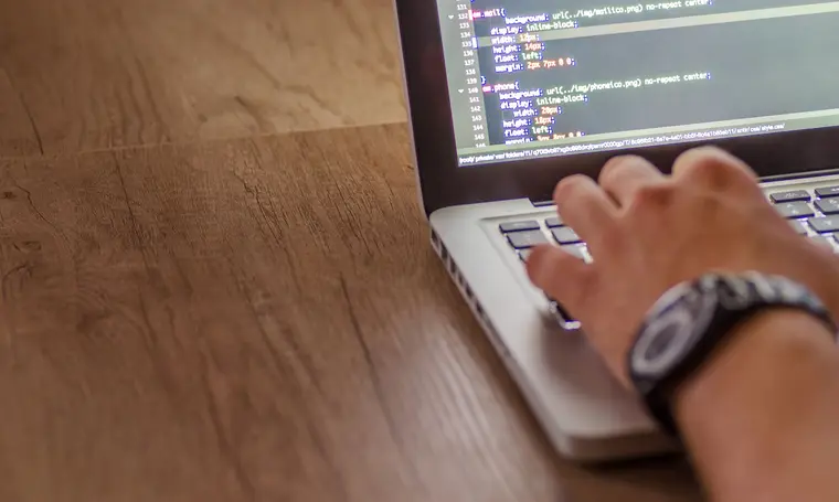 Close-up of a person coding on a laptop, showcasing web development and programming concepts.