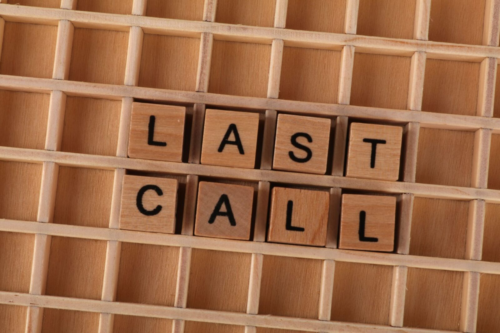 Wooden letter tiles forming the phrase 'Last Call' on a wooden background.